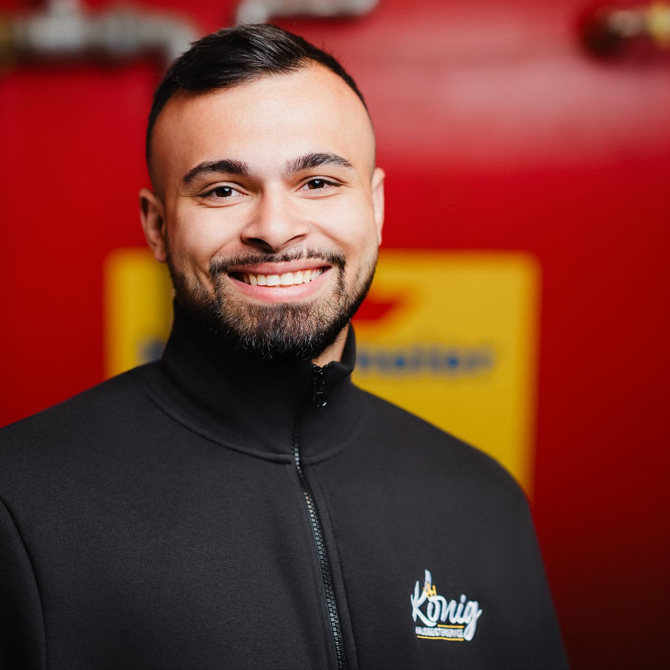 Ein lächelnder Mitarbeiter des Hausmeisterservice König in Firmenkleidung, der die gute Laune und das sympathische Team in Köln repräsentiert.