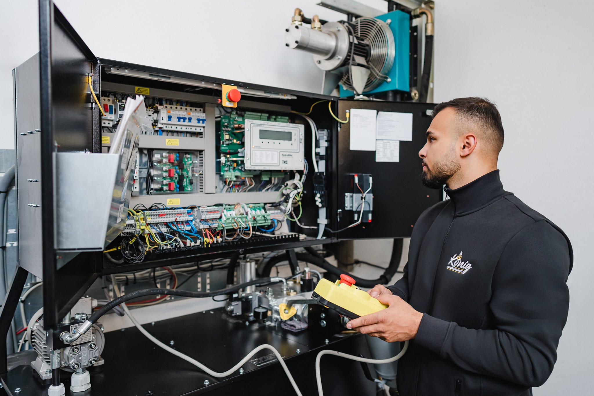 Ein kompetenter Mitarbeiter von König Hausmeisterservice bei der proaktiven technischen Objektkontrolle und Prüfung der Haustechnik an einem geöffneten Schaltschrank.